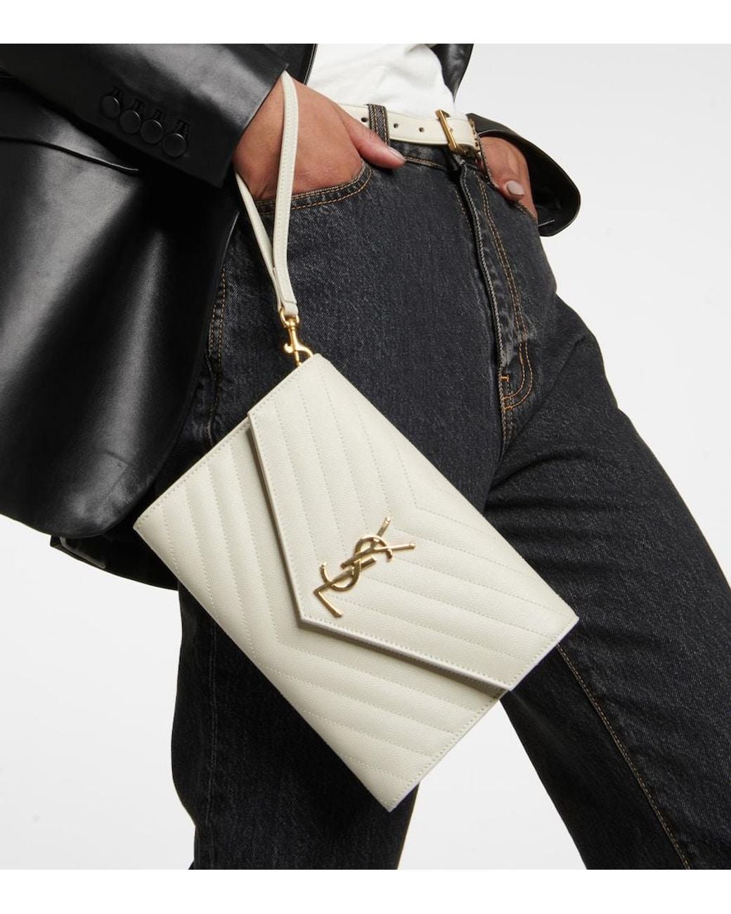 Model carrying a pale Saint Laurent Cassandre Matelassé Clutch with gold hardware.