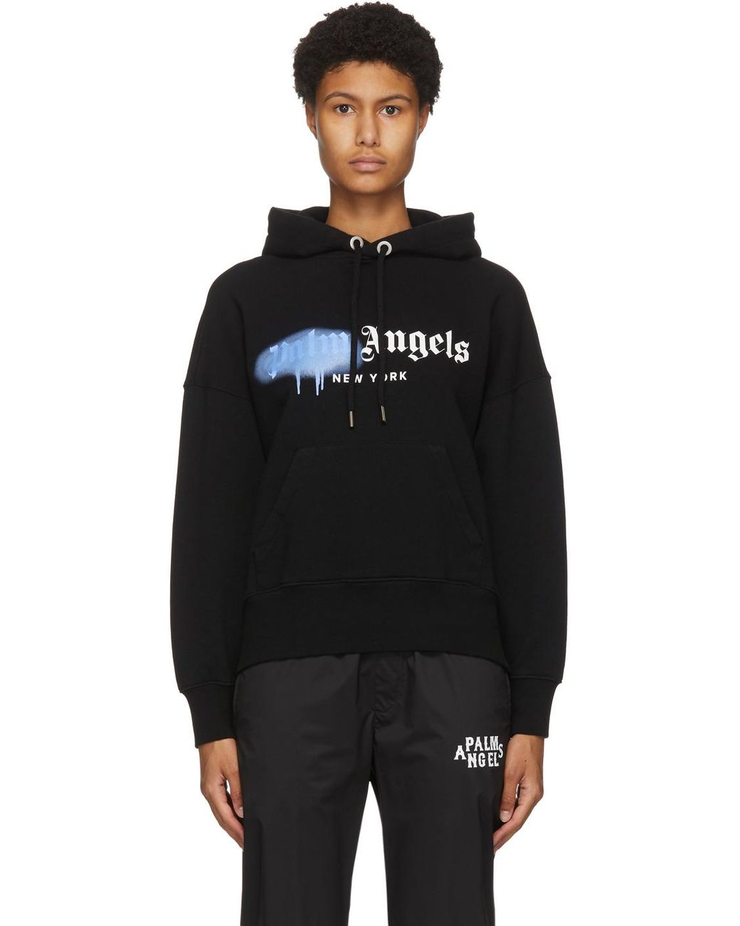 https://cdna.lystit.com/1040/1300/n/photos/ssense/8b8e6319/palm-angels-BlackBlue-Black-new-York-Sprayed-Logo-Hoodie.jpeg