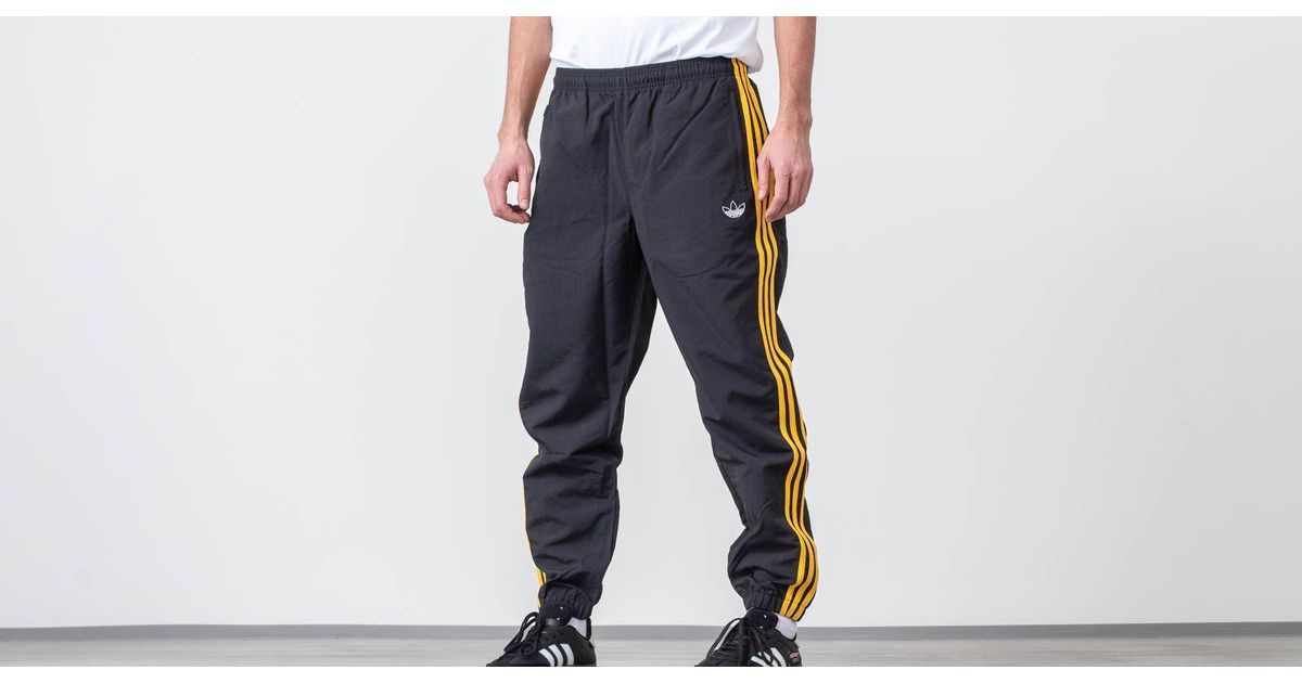 black adidas pants with gold stripes