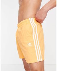 Adicolor - pantaloncini da bagno arancioni con tre strisce da Uomo di adidas  Originals in Arancione | Lyst