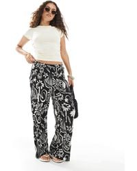 Vero Moda - – plissee-hose mit hohem bund, weitem bein und tropischem blumenmuster - Lyst