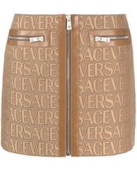 Versace - Minigonna con zip e stampa logo lettering all-over in canvas marrone donna - Lyst