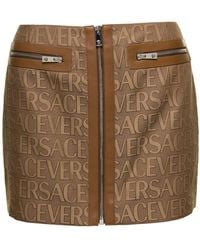 Versace - Minigonna con zip e stampa logo lettering all-over in canvas marrone donna - Lyst