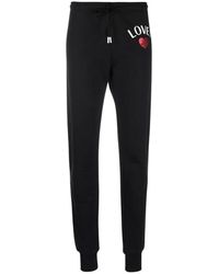 Femme Vêtements Articles de sport et dentraînement Pantalons de survêtement/sport Pantalon de jogging slim à logo imprimé Coton Moschino en coloris Noir 