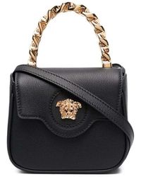 Versace - Mini borsa nera con manico in tono oro - Lyst