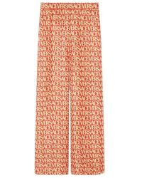 Versace - Logo Printed Wide Leg Trousers - Lyst