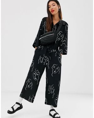 Monki – er Jumpsuit mit Gesicht-Print und Kordelzug an der Taille - Schwarz