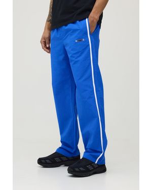 BoohooMAN Relaxed Fit Side Stripe Logo Print Nylon Trousers - Blue