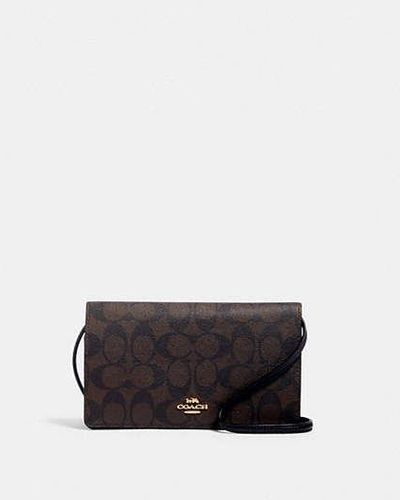 COACH Bolso de mano cruzado Anna con solapa en lona de firma - Negro