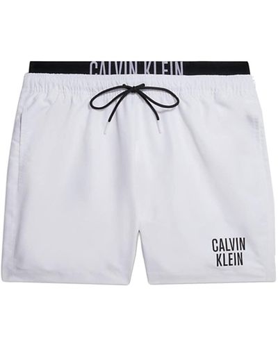 Calvin Klein CK mer Boxer Piscine Maillot de Bain avec Logo imprimé avec élastique Apparent Article KM0KM00740 - Blanc