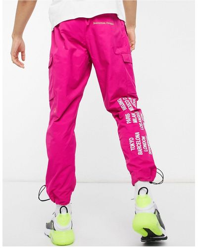 Nike World tour pack - jogger à chevilles resserrées, poches cargo et imprimé graphique - Rose