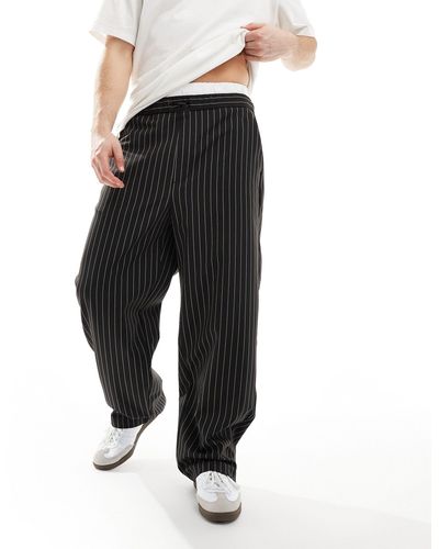 Bershka Pantaloni sartoriali con fondo ampio neri a righe con dettaglio boxer - Nero