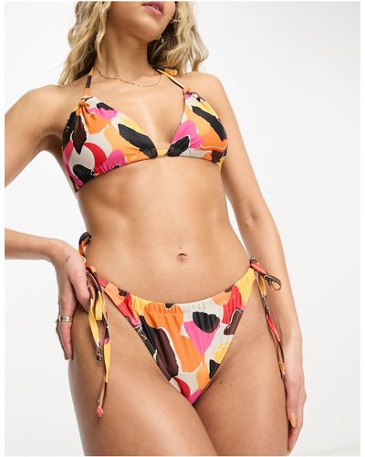 We Are We Wear Melissa - slip bikini con stampa rétro stile giornale con allacciatura laterale - Rosso