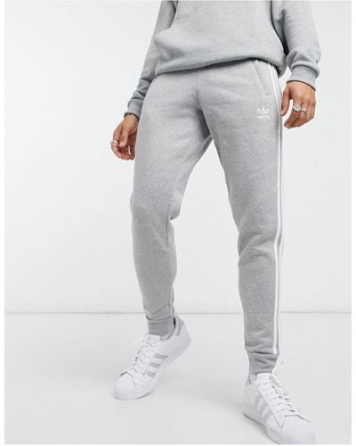 adidas Originals – adicolor – eng geschnittene jogginghose mit den drei streifen - Grau