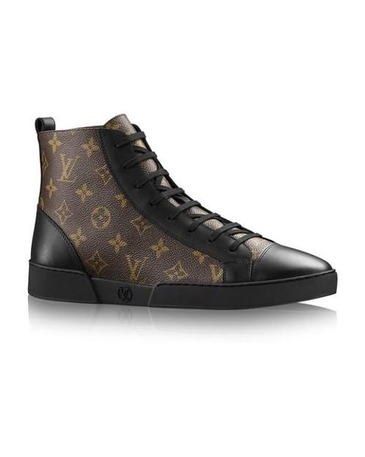 Man with black leather Louis Vuitton boots with golden logo before