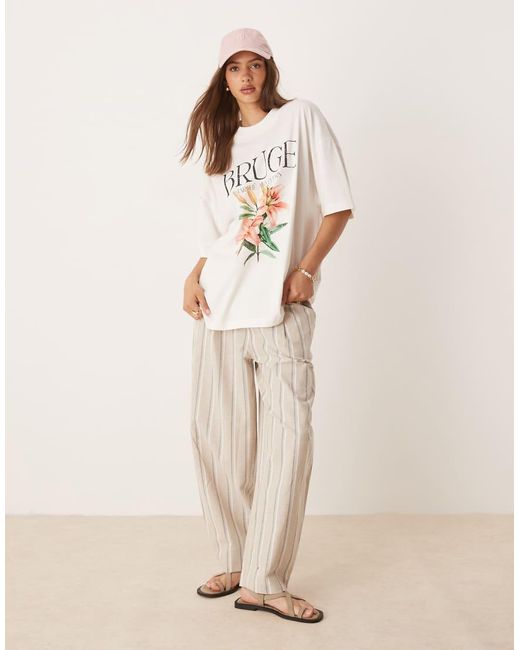 Camiseta Extragrande Con Estampado Gráfico De Flor Y Texto "Bruge" De -Blanco ASOS de color Natural