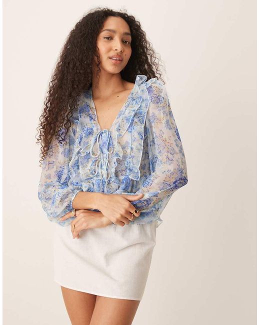 Blusa Pastel Vaporosa De Manga Larga Con Estampado Floral, Volantes Y Detalle De Lazada De Mango de color Blue