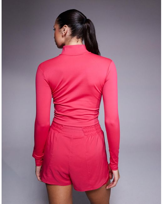 Nike - one training - top manches longues ajusté à col zippé Nike en coloris Pink