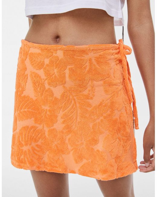 Mini-jupe croisée d'ensemble en tissu éponge à fleurs Bershka en coloris Orange