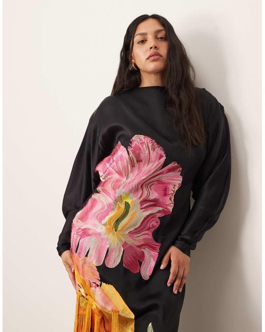 Curve - robe longue à dos ouvert et épaules marquées avec broderies fleuries et franges ARRANGE en coloris Black