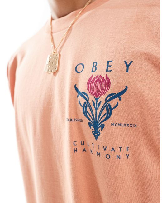 T-shirt con grafica "cultivate harmony" di Obey in Pink