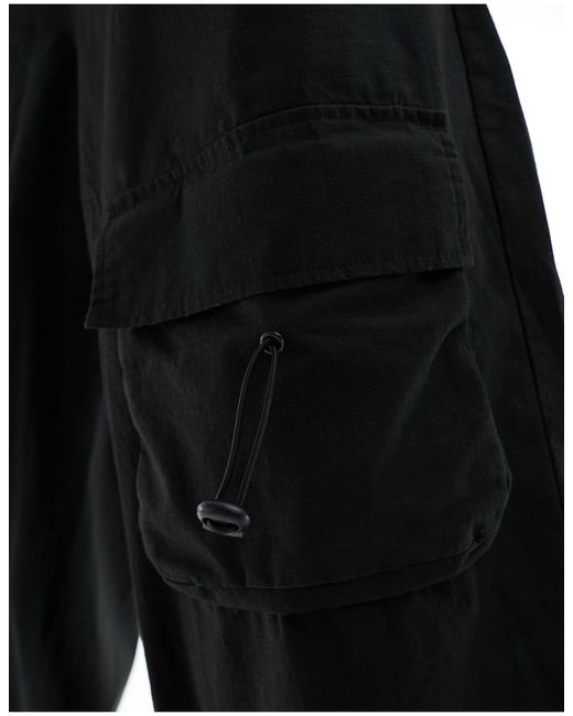 Pantaloni cargo larghi neri con tasche elasticizzate sul davanti di ASOS in Black da Uomo
