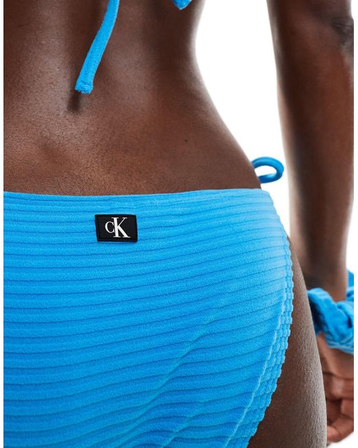 Slip bikini a coste con laccetti laterali e monogramma ck di Calvin Klein in Blue