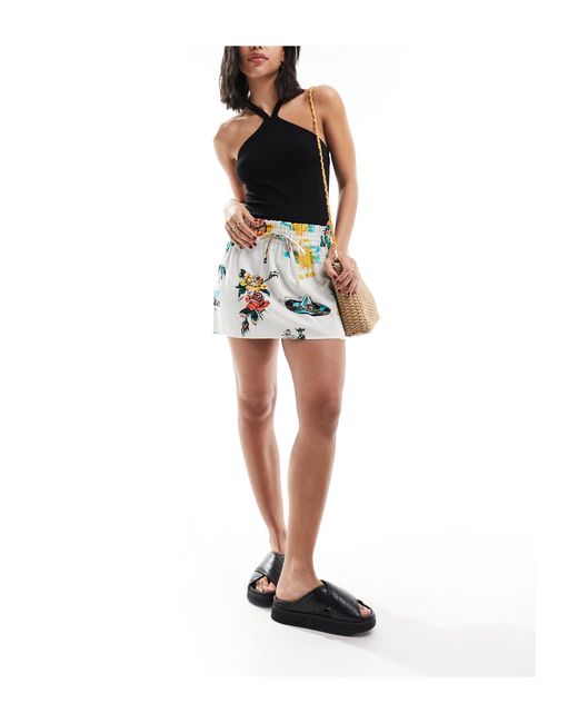 Mini-jupe nouée à la taille en aspect lin imprimé tropical ASOS en coloris Black