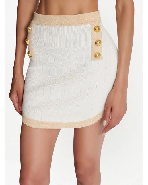 Minigonna bianca a matita con bottoni e finiture oro di Balmain in White