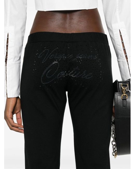 Pantaloni crop con logo in cristalli di Versace in Black
