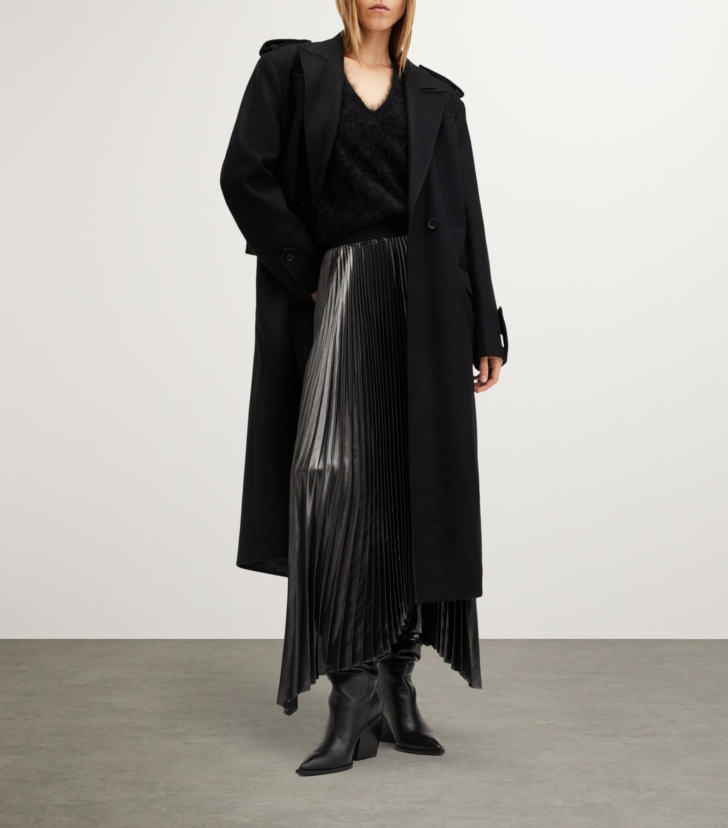 Woman in black trench coat with metallic pleated skirt